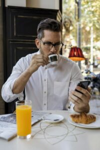 Businessman having breakfast in a cafe and checking cell phone